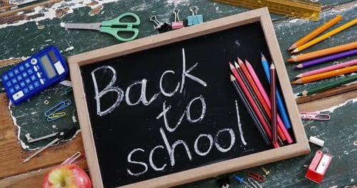Text written on slate with school supplies