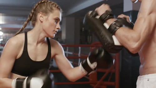 Female Boxer Training with Pads in Boxing Ring