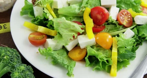 Vegetable salad with granola bar and measurement tape