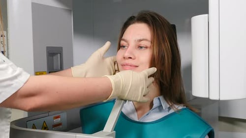 Radiologe in der Zahnklinik, der den Kopf der Patientin vor dem MRT-Eingriff anpasst,