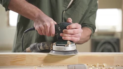Carpenter Smoothing Wood Plank with Electric Sander