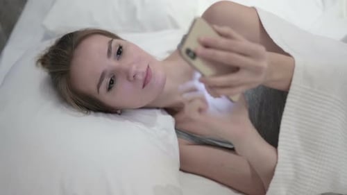 Woman in Bed Using Smartphone at Home