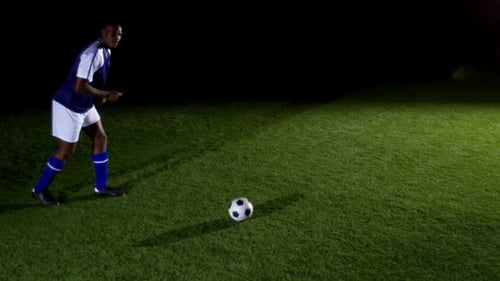 Soccer Player Kicking Soccer Ball at Night