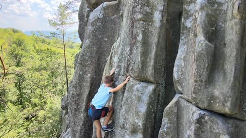 Determined Boy Climber Clambering Up Steep Wall of Rocky Mountain