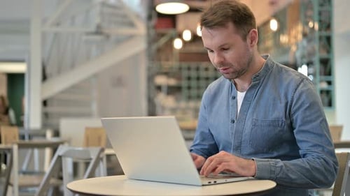 Hombre casual profesional usando una computadora portátil en un café