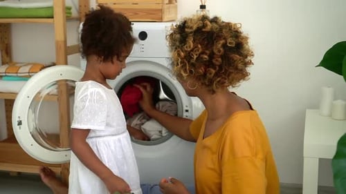 Afro Mama und Tochter Load Washer mit schmutziger Kleidung Spbd