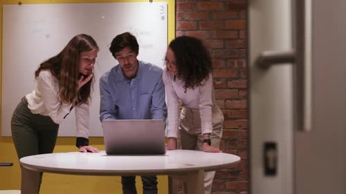 Creative businesspeople discussing over laptop in modern office