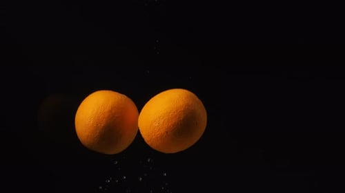 Fresh Oranges Slowly Sink into Water