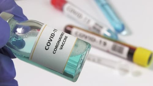Hand Holds Covid-19 Vaccine with Test Tubes