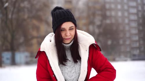 Close Up of Young Woman in Hat Puts on Red Jacket Standing on Street