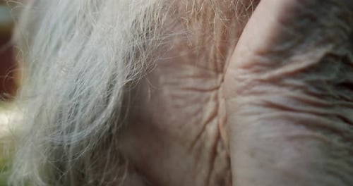 Nahaufnahme einer älteren alten Frau mit faltiger Hand wischt ihr Auge mit der Hand ab und sieht gerade aus