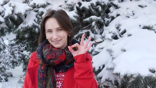 Smiling Woman in Winter Makes OK Gesture