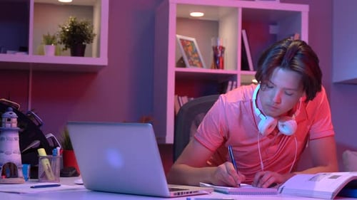 Teen Working on Laptop and Writing at Desk