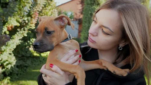 Woman Cuddling Puppy in a Suburban Garden