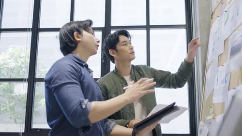 Young Men Collaborating on Project in Modern Office