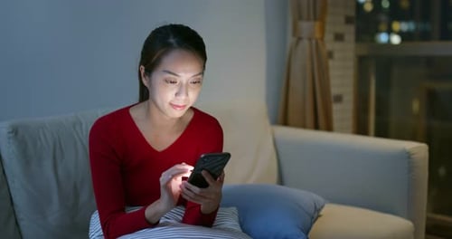 Woman on Phone at Night in Brightly Lit Room