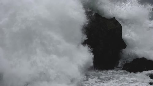 Slow motion of powerful waves crashing after hitting the rocks on the seashore. Close up.