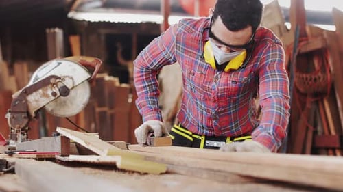 Carpenter working on woodworking machines in carpentry shop