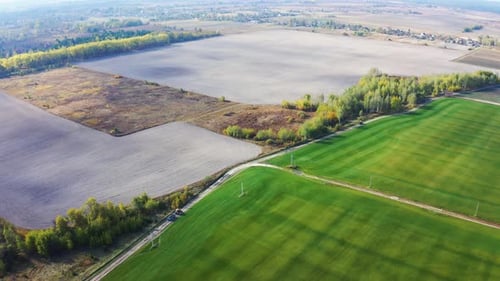 Aerial Fly Over Beautiful Field Landscape. Tractor Rides on the Road Past the Green Fields of the