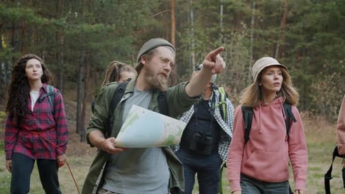 Slow Motion of Young Tourists Walking in Forest Looking at Map and Gesturing Discussing Trip