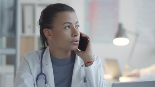 Young Female Doctor on a Phone Call at Desk