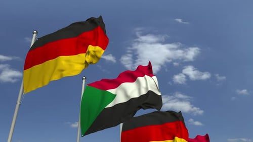 Waving Flags of Germany and Sudan in a Blue Sky