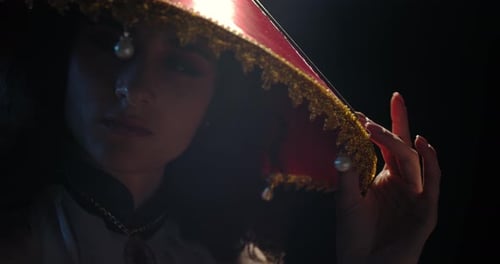 Woman Posing with Ornate Hat in Dramatic Lighting