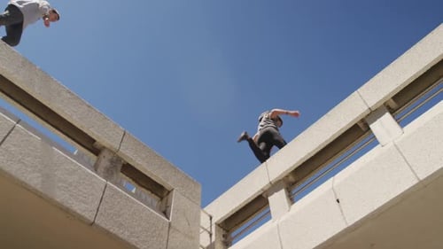 Athletic Young Adults Parkour Jump Between Structures