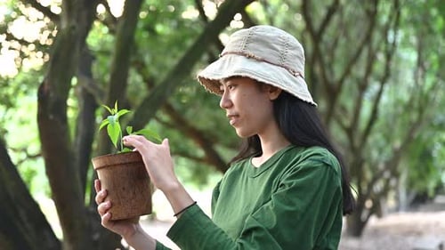 Young Woman Holding Potted Plant and Smiling
