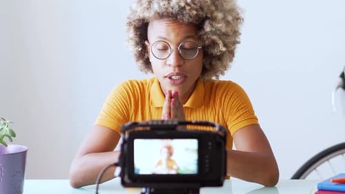 Woman Speaking into Camera at Desk
