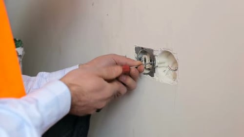 Electrician Fixing Outlet Inside Wall With Screwdriver