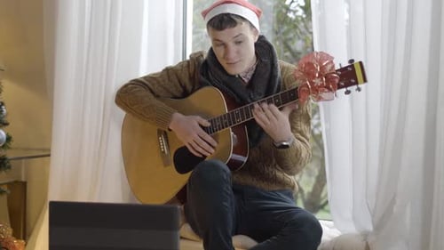 Young Adult Plays Guitar with Christmas Decoration