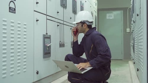 Engineer Using Laptop and Walkie Talkie at Work