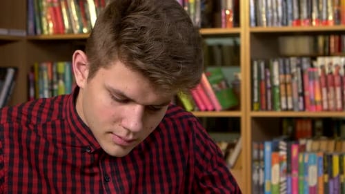 Student Using His Digital Tablet in a Library, Preparing for Abstracts. Close Up