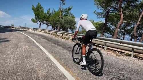 Male cyclist in white helmet and white cycling jersey riding bicycle
