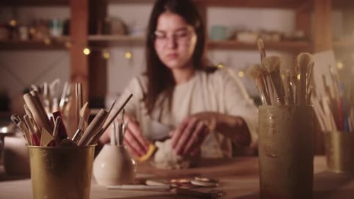 Woman Smoothing Clay for Pottery in Warm Workshop