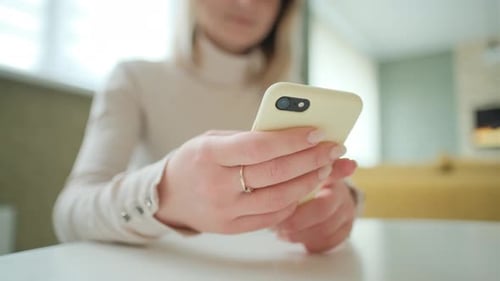 Close-up of Female Hands Using Smart Phone at Modern Home Interior. Businesswoman Is Typing a Text