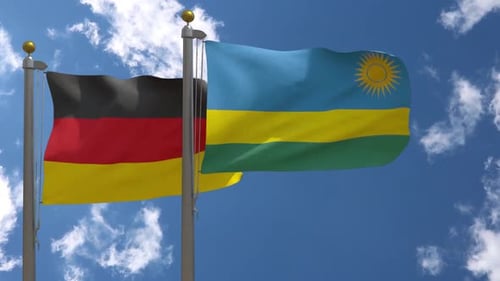 Germany and Rwanda Flags Waving on Poles Against Blue Sky
