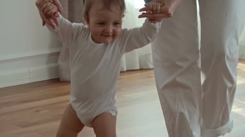 Smiling Infant Taking First Steps With Adult