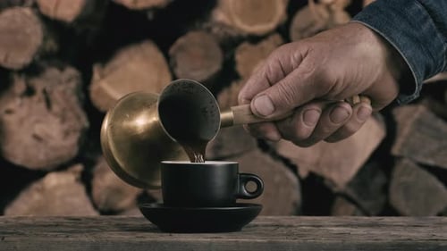 Pouring Hot Coffee from Turkish Pot Into Cup