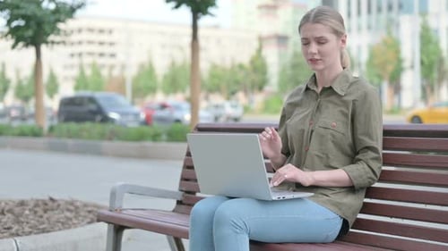 Woman with Neck Pain Using Laptop on Park Bench