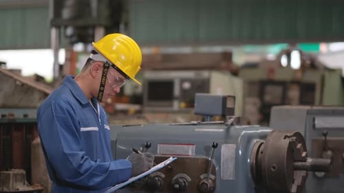 Factory man or technician worker with blue uniform and yellow hardhat check the function of machine