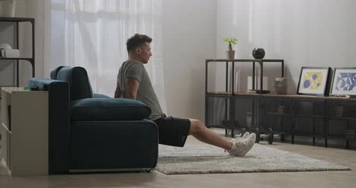 Morning Workout of Adult Sportsman at Home Man Is Using Couch As Gym Equipment Lifting His Own