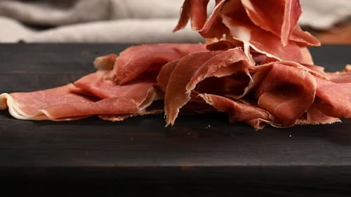 Jamon tranché sur une planche de bois, petit déjeuner.