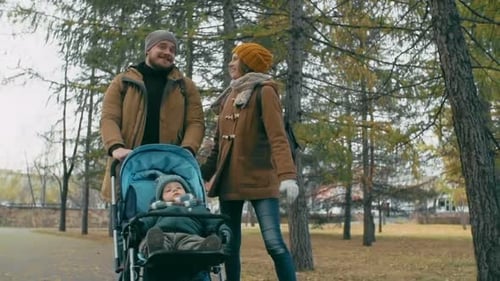 Family Walking with Stroller in Autumn Park
