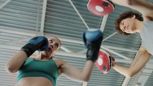 Slow Motion of Female Boxer Training with Professional Instructor During Personal Practice in Gym
