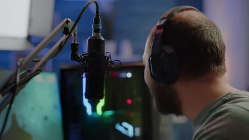 Man wearing headphones talking into microphone in studio