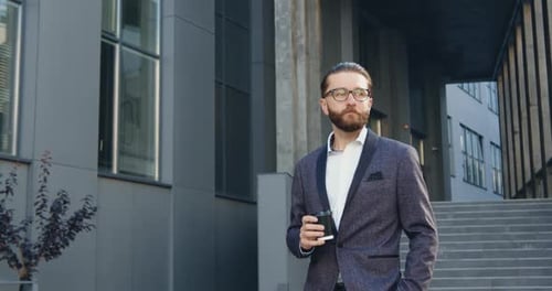 Office Worker Which Drinking Coffee from Paper Cup while Walking Near Modern City Building