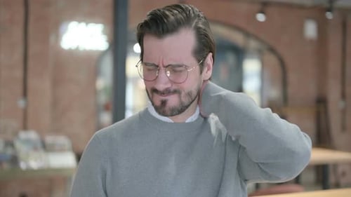 Man Massaging his Neck Indoors
