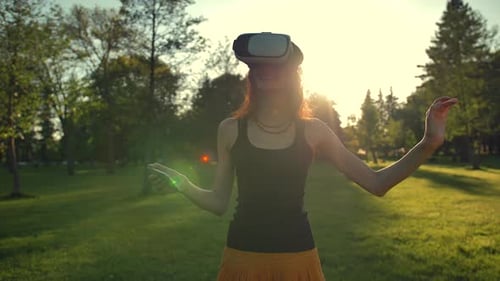 Beautiful Caucasian Woman Enjoy Virtual Reality Walking on Grass in Park.